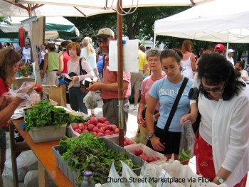 people shop for vegetables at a farmers market stand